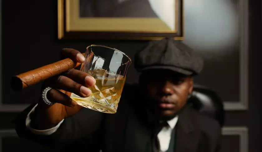 a man holding a glass of alcohol and a cigar