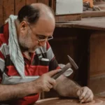 a bald man is hammering the nail