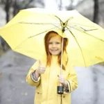 a girl wearing a yellow dress is holding an umbrella