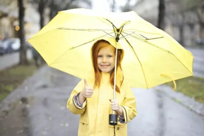 a girl wearing a yellow dress is holding an umbrella