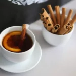 A white cup of cinnamon sticks and tea