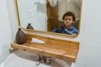 a boy is holding a brush on the front of the mirror