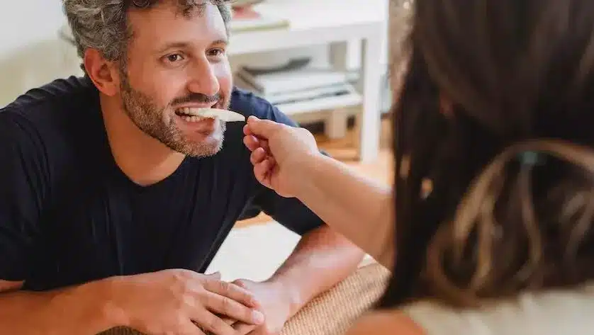 a man is eating something from a woman's hand