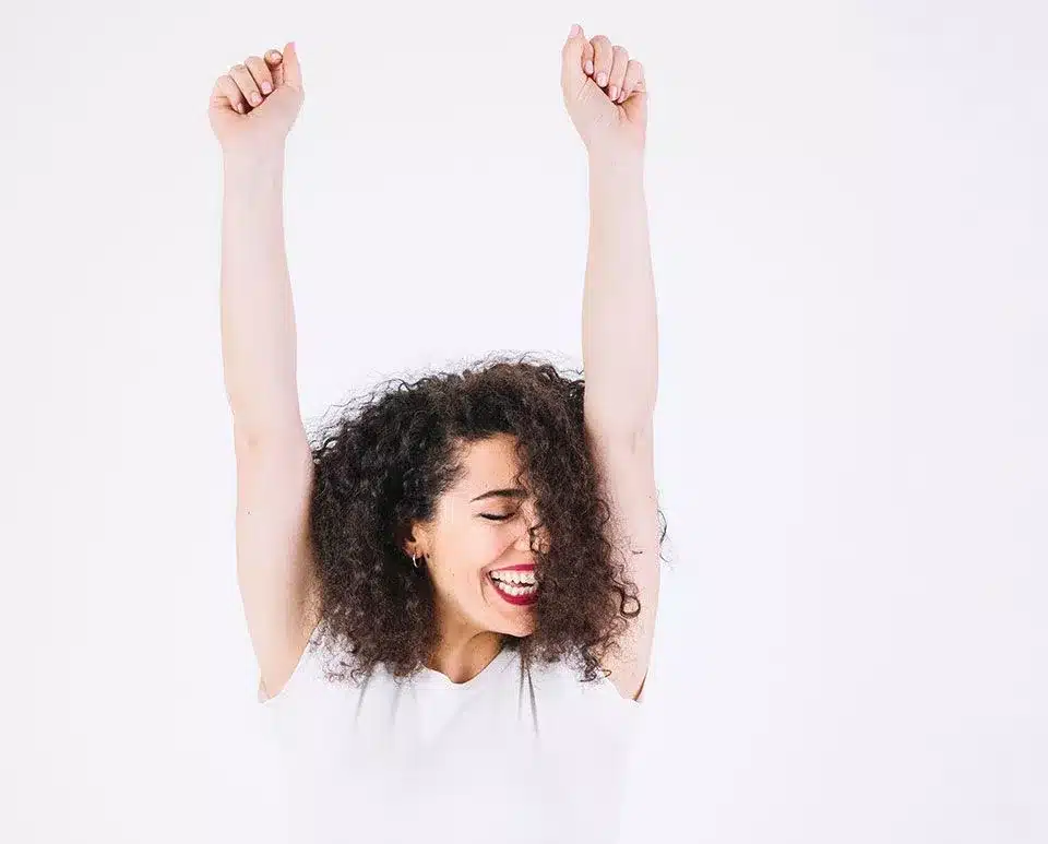 a woman is laughing with her hands up