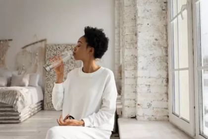 A woman dressed in white is drinking water