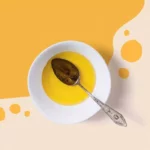 There is oil and spoon in a bowl and the oil has spilled out