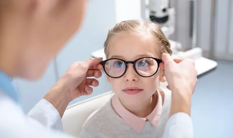 A doctor test glasses on a girl