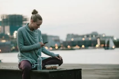 A girl is operating her mobile while sitting on the bench