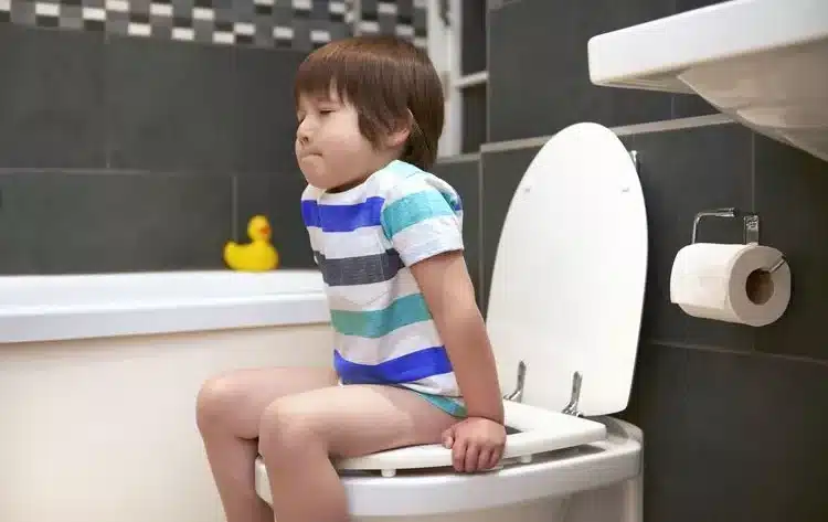 a child is sitting on the toilet due to constipation