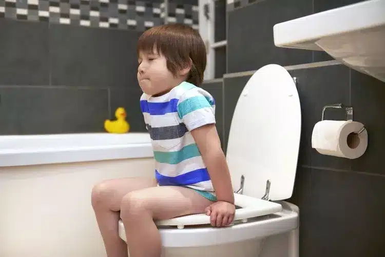 a child is sitting on the toilet due to constipation
