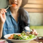 A girl is shown eating green vegetables
