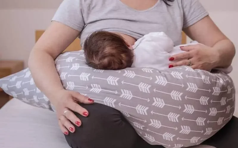 A woman breastfeeding a baby during a blocked milk duct condition