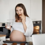 A pregnant lady eating a food