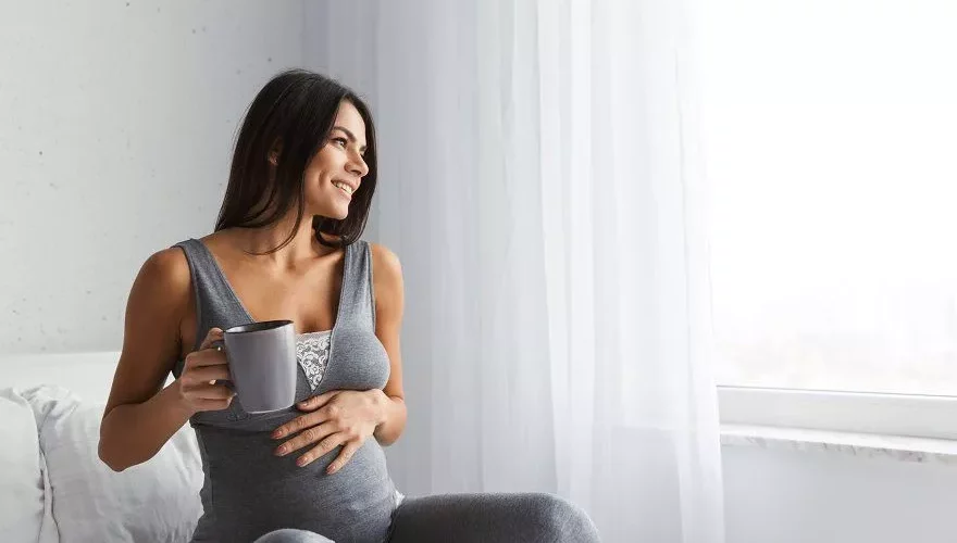 a pregnant woman hold a cup