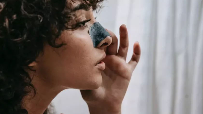 a girl using a clay mask on her nose to remove blackheads