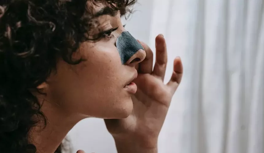 a girl using a clay mask on her nose to remove blackheads