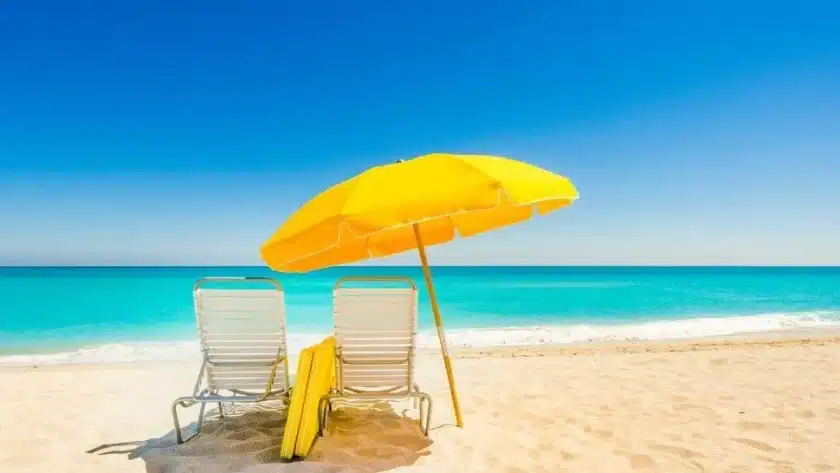 two chairs and a blue umbrella are kept on the beach