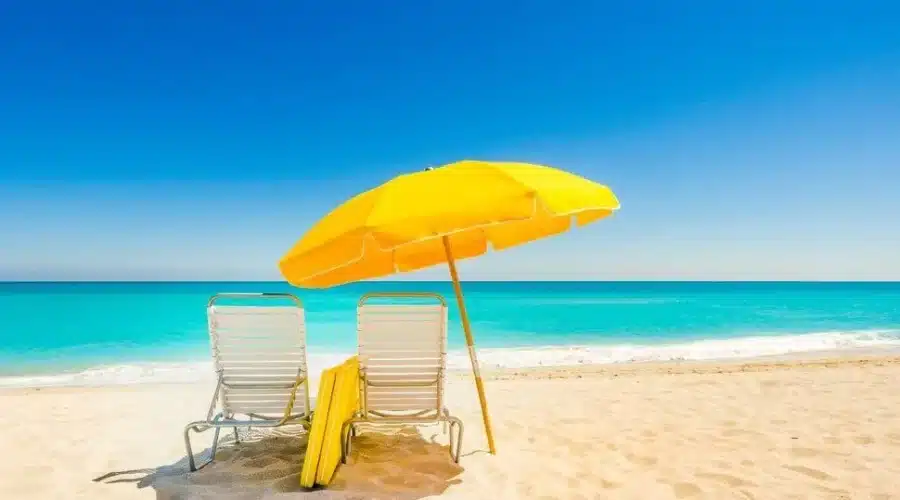 two chairs and a blue umbrella are kept on the beach
