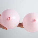 a hand is holding two pink balloons