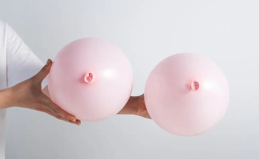 a hand is holding two pink balloons