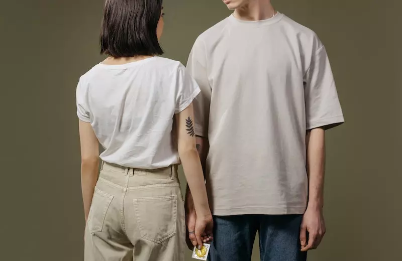 a girl standing with a men and holding a condom